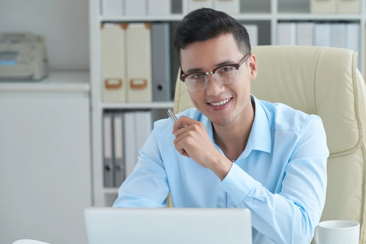 Young man working on social media strategies on the laptop and smiling.